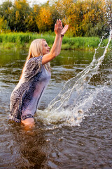 beautiful cheerful woman in the river with water splashes