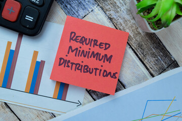 Concept of Required Minimum Distributions write on sticky notes isolated on Wooden Table.