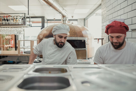 Workers inside a kitchen of a pizzeria restaurant