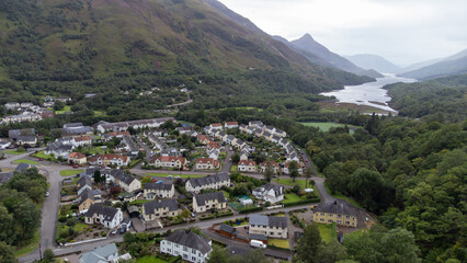 The Scottish village of Kinlochleven as seen from a drone point of view. In the background the Loch Leven (Lake Leven) can be seen, flanked by the Mamores ridge and Glen Coe. - obrazy, fototapety, plakaty