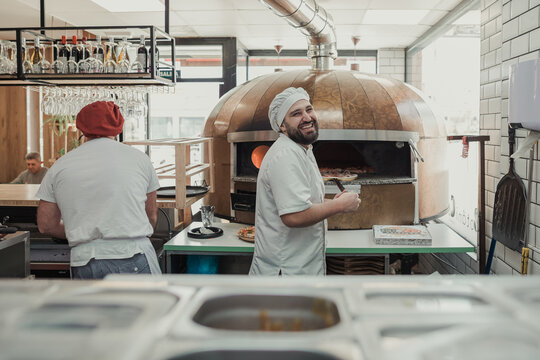 Happy worker in a kitchen of a pizzeria restaurant