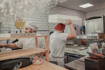 Overworked men working in the kitchen of a pizzeria restaurant - obrazy, fototapety, plakaty