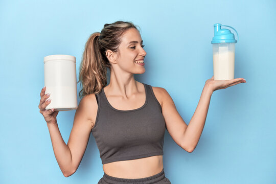Athlete with protein shake and container in blue studio