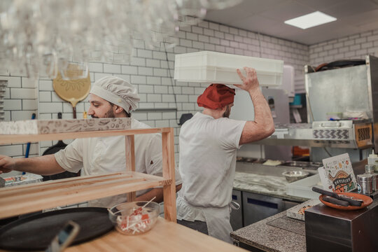 Overworked men working in the kitchen of a pizzeria restaurant