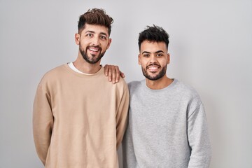 Young homosexual couple standing over white background with a happy and cool smile on face. lucky person.