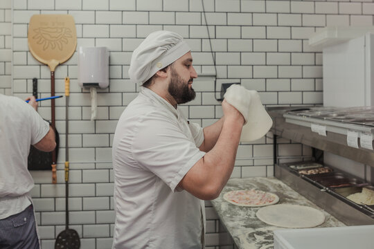 Man kneading a pizza dough in the air