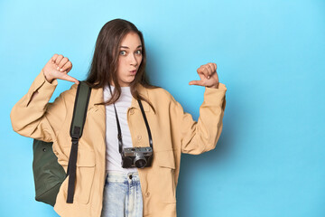 Young Caucasian woman traveler with camera and backpack feels proud and self confident, example to...