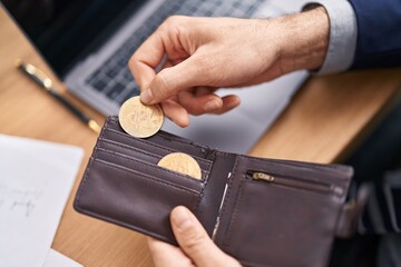 Young hispanic man business worker holding wallet and bitcoin at office