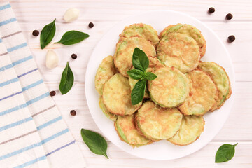 Baked zucchini with cheese, garlic and fresh herbs on a white wooden background.