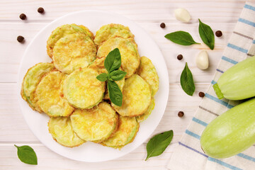 Baked zucchini with cheese, garlic and fresh herbs on a white wooden background.