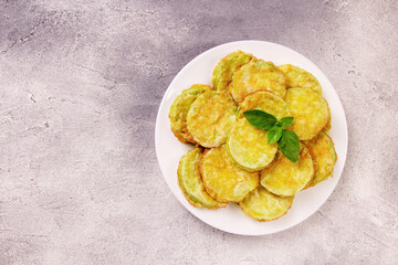 Baked zucchini with cheese, garlic and fresh herbs on a gray background.