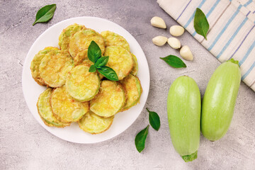 Baked zucchini with cheese, garlic and fresh herbs on a gray background.