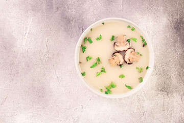 Homemade mushroom soup in a bowl on a gray background.