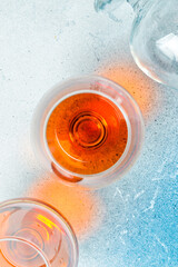 Two glasses with cognac or brandy on a stone table. Strong aged alcoholic drinks. On a concrete background.