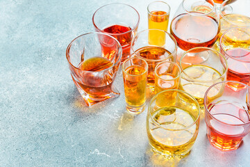 A set of glasses with strong alcoholic drinks: whiskey, brandy, cognac or bourbon and rum. Side view. Strong aged alcoholic drinks. On a concrete background.