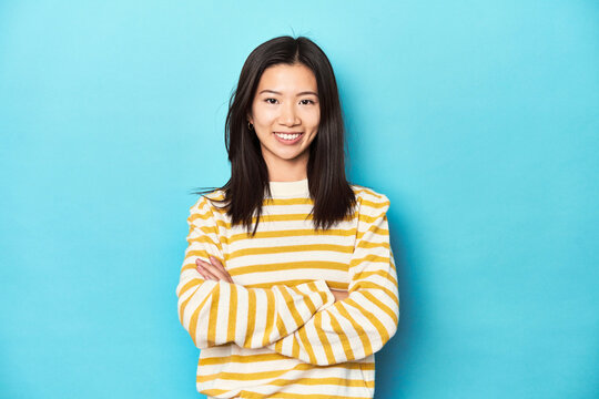 Asian Woman In Striped Yellow Sweater, Who Feels Confident, Crossing Arms With Determination.