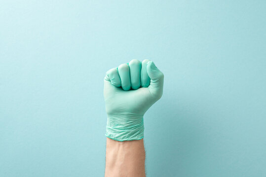 Necessity of regular medical check-ups concept. High angle view picture of doctor's hand in fist in sterilized glove on teal background with copy-space for text or promotional messages