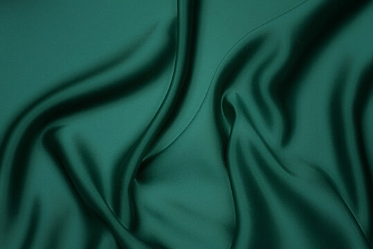 Texture, background, pattern. Texture of green silk fabric. Beautiful emerald green soft silk fabric.