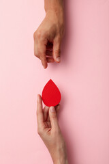 Paper drop of blood in the hand on a light background. Blood donation