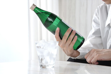 焼酎の水割りと酒の銘柄を確認する男性