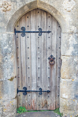 Wooden old house's door with an iron knock nob and door hinges