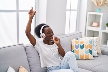 African american woman listening to music singing song at home