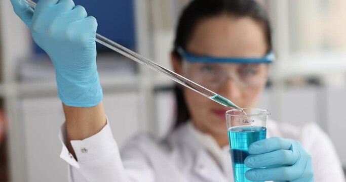 Scientist drips blue liquid from pipette into test tube. Study of chemical toxic liquids in the lab