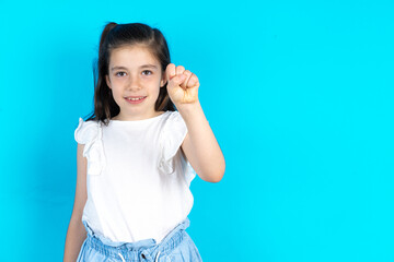 Fototapeta premium Caucasian kid girl wearing white t-shirt over blue background pointing up with fingers number ten in Chinese sign language Shi