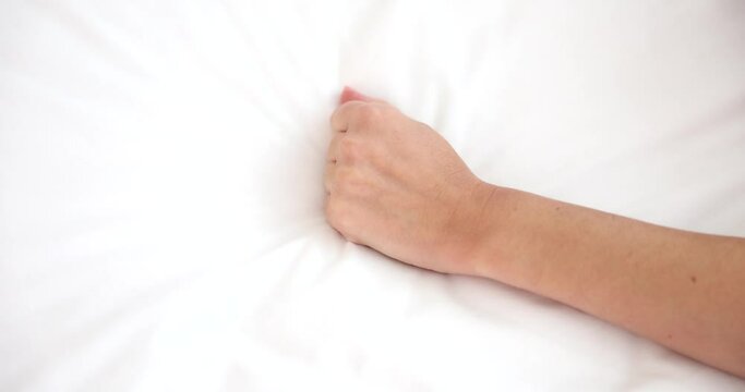 Sexy female hand pulls and squeezes white sheets in bed. Female sexual disorders and frigidity