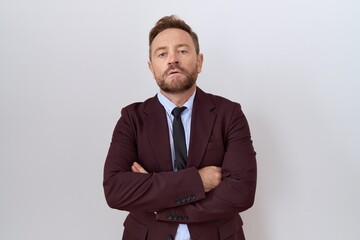 Middle age business man with beard wearing suit and tie skeptic and nervous, disapproving expression on face with crossed arms. negative person.