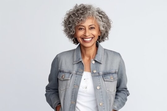 Medium shot portrait of an Indian woman in her 60s wearing a denim jacket against a white background