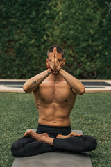 man doing yoga meditation in a park