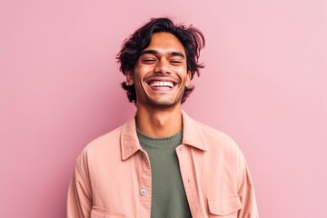 Fototapeta premium Portrait of a happy young indian man laughing on pink background