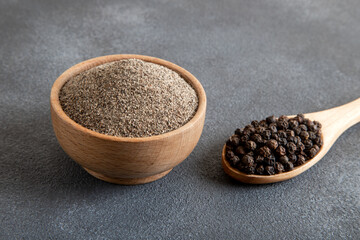 Ground black pepper with grains of black pepper on dark background