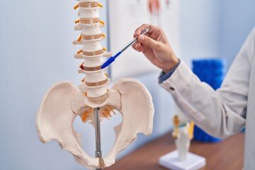 Young blonde woman pysiotherapist pointing to anatomical model of vertebral column at rehab clinic