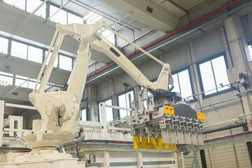 Mechanical crane arm for moving boxes in an industrial plant, no people are visible. 