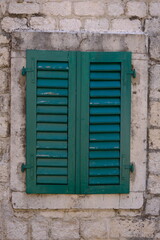 window of the stone house with a green shutter