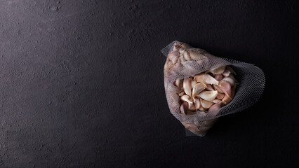 Top view of raw garlic in net bag on gray background