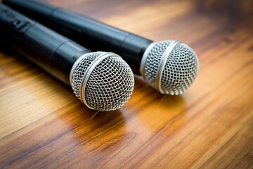 Obraz premium Two radio microphones lying on a wooden table surface.