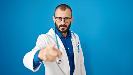 Young hispanic man doctor angry pointing with finger over isolated blue background