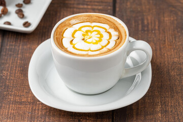 Patterned cappuccino coffee in a white porcelain cup on a wooden table