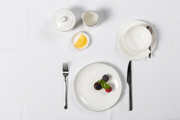 Various setup servings with plate, fork, knife on white table