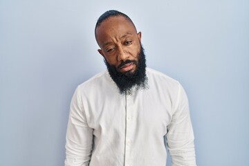 African american man standing over blue background looking sleepy and tired, exhausted for fatigue and hangover, lazy eyes in the morning.