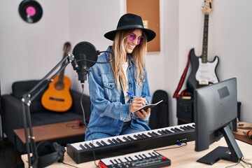 Young woman musician smiling confident composing song at music studio