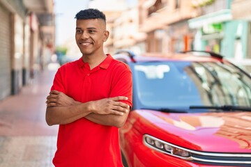 Young latin man smiling confident standing with arms crossed gesture at street