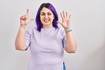 Plus size woman wit purple hair standing over isolated background showing and pointing up with fingers number seven while smiling confident and happy.