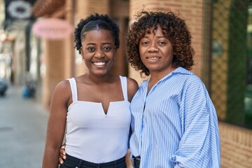 African american women mother and daughter hugging each other at street