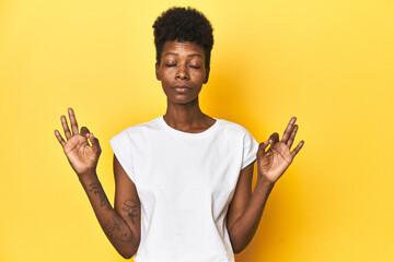Elegant African woman, short hair, white tank top, Elegant African woman, short hair, white tank toprelaxes after hard working day, she is performing yoga.