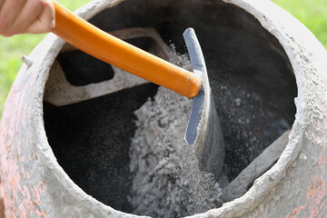Construction site. Adding lime, sand and stones to rotating cement mixer. Builder working with...