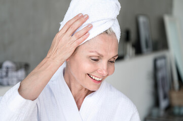 Smiling middle age woman with towel on head after washing hair
